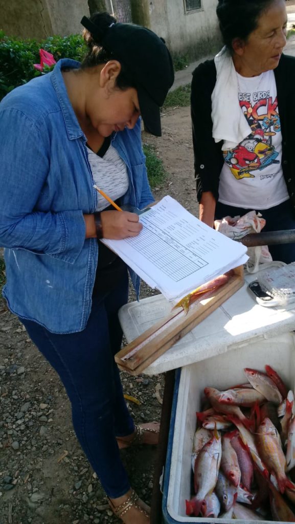 Ana Valdez marks down measurements of a fisherman's catch
